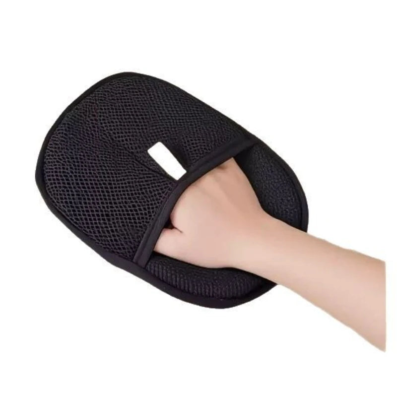 Hand holding a black oval Pet Grooming Glove with textured surface and thumb opening