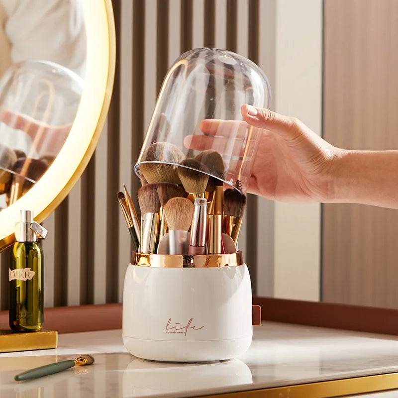 Hand placing the clear dome on a 360° Rotating Makeup Brush Storage Box filled with brushes